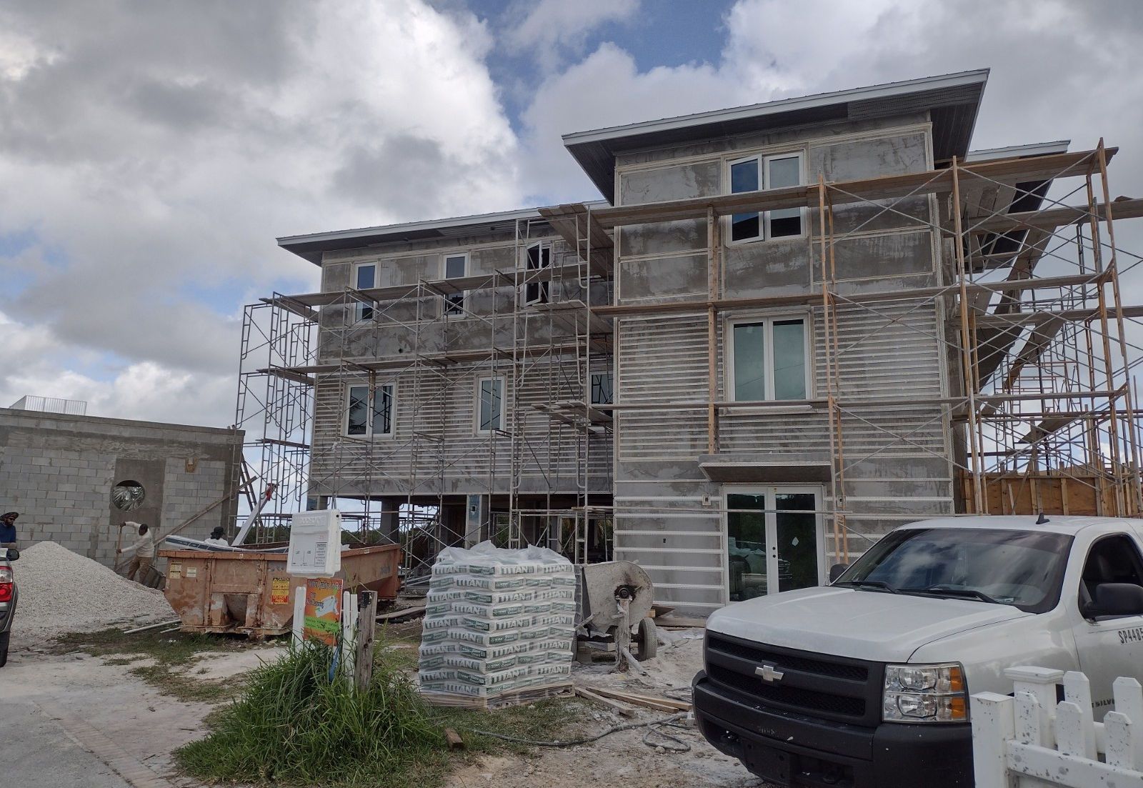 A white truck is parked in front of a building under construction.