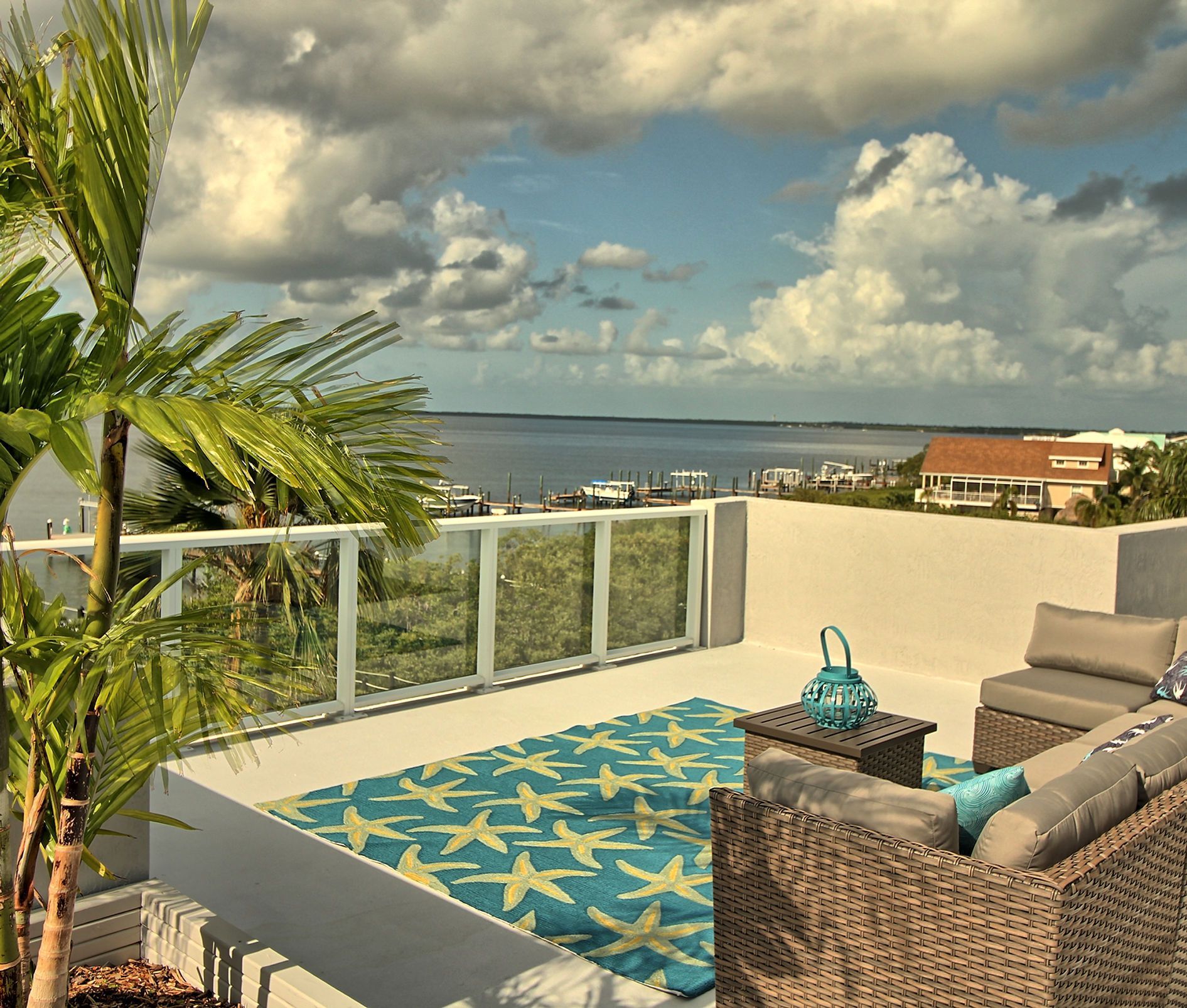 A balcony with a view of the ocean and a couch and chairs