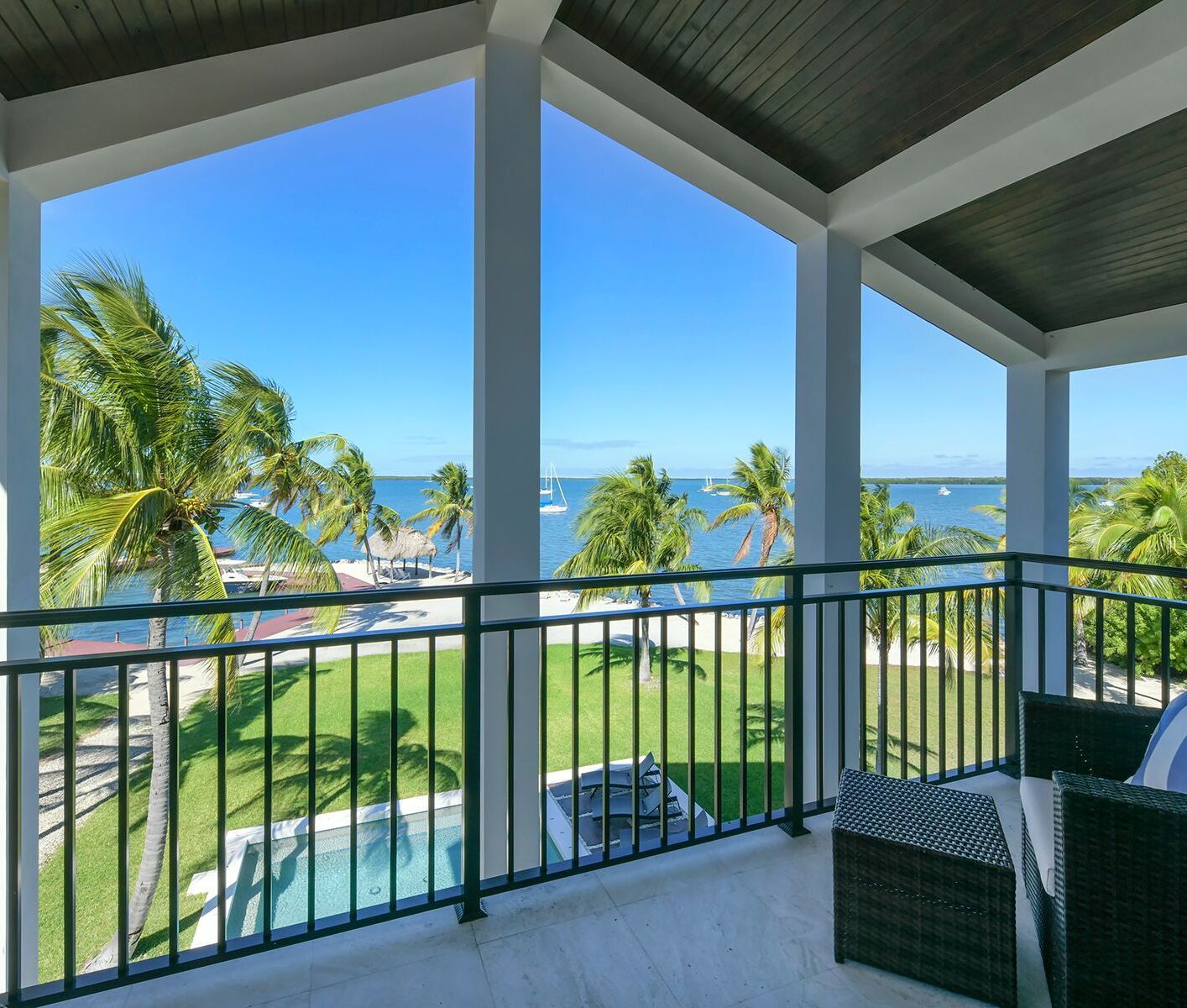A balcony with a view of the ocean and palm trees