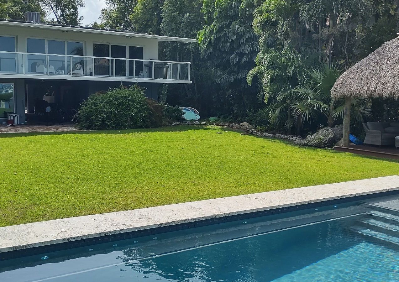 There is a large swimming pool in the backyard of a house.