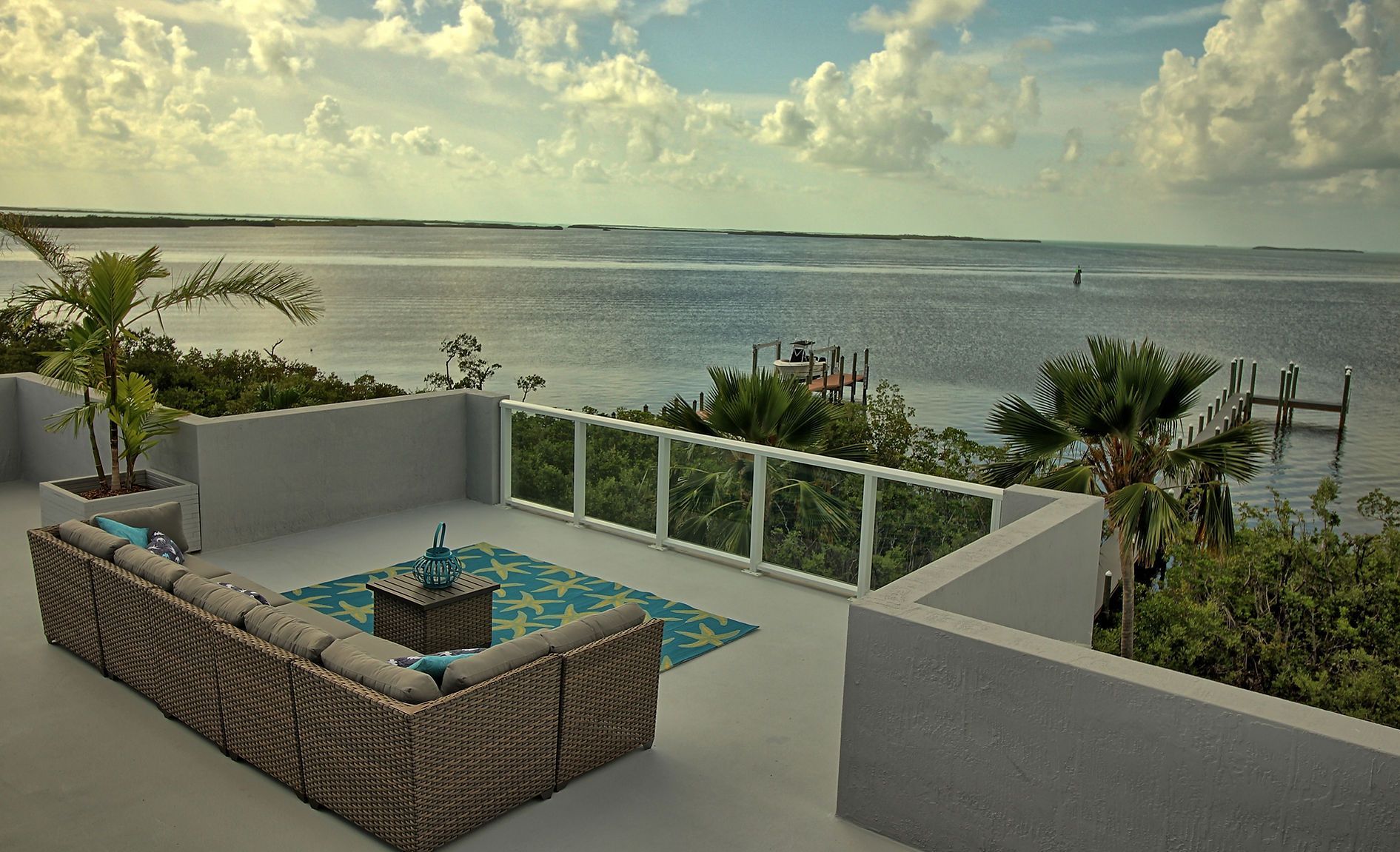 A patio with a couch and a table overlooking the ocean.