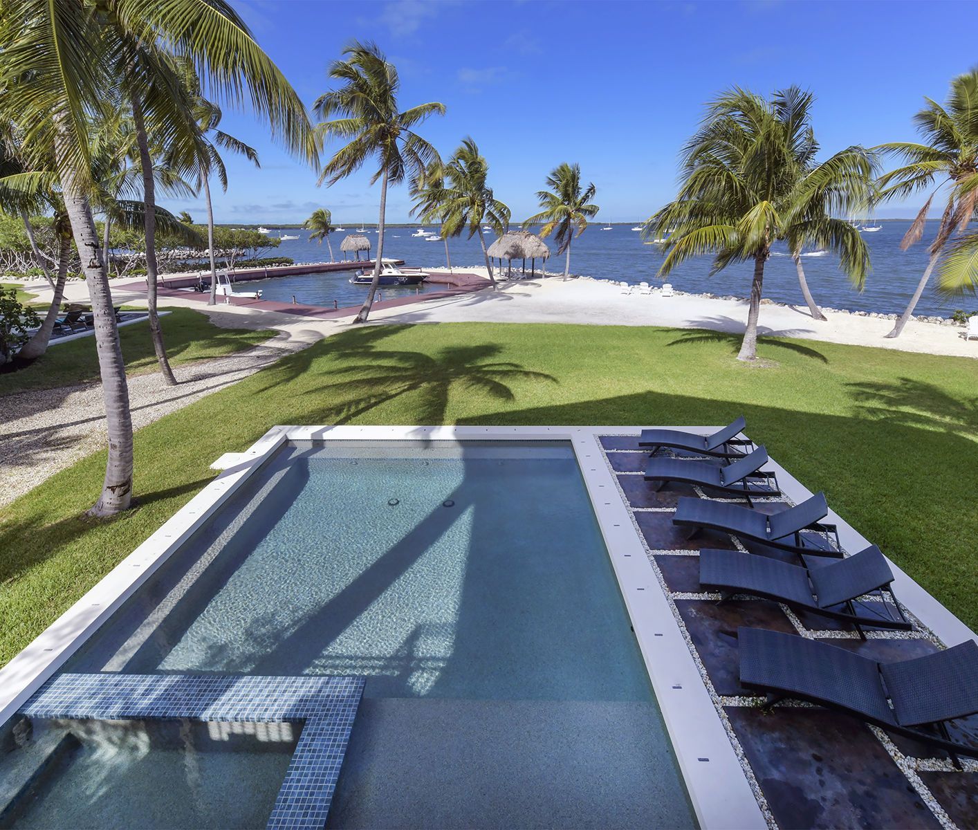 A large swimming pool surrounded by lawn chairs and palm trees