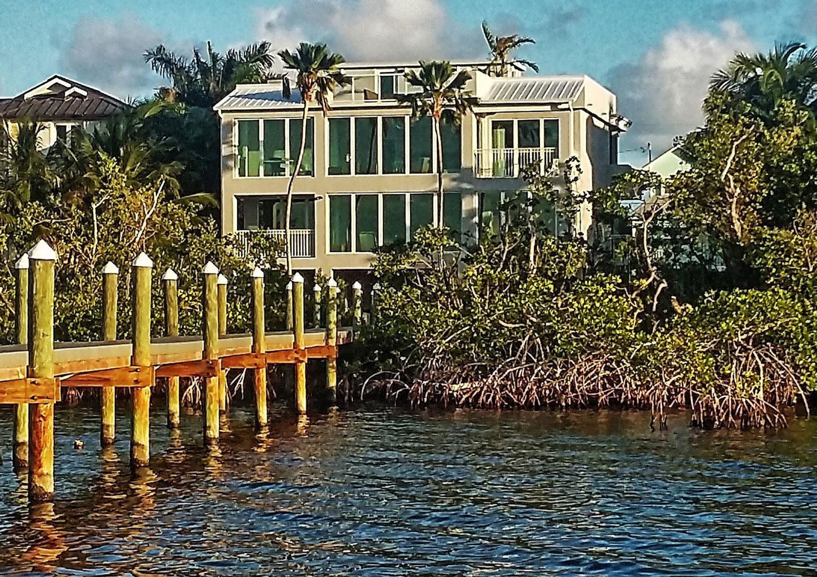A large house sits on the shore of a body of water