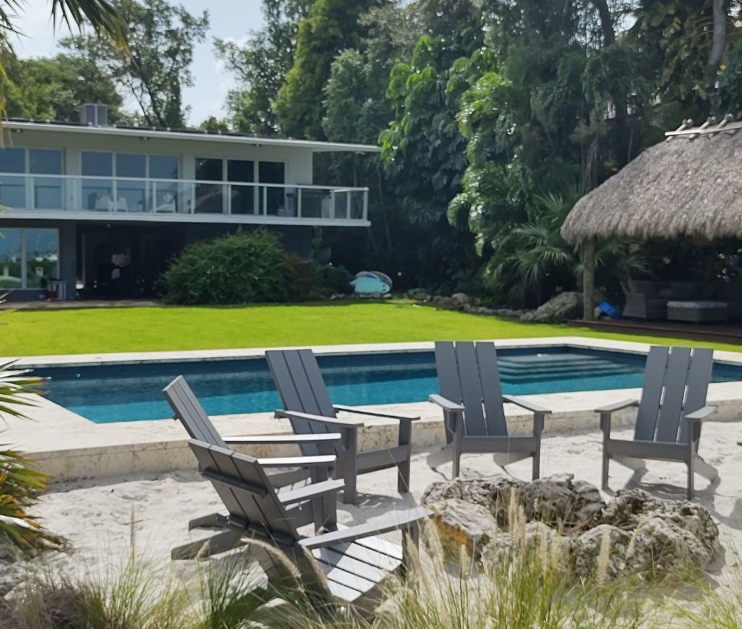 A large house with a pool and chairs in front of it