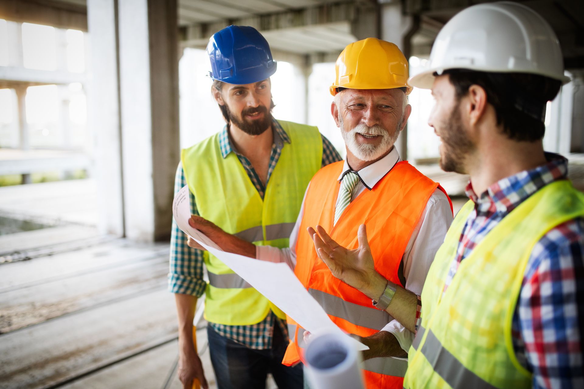 A group of construction workers are looking at a blueprint on a construction site.