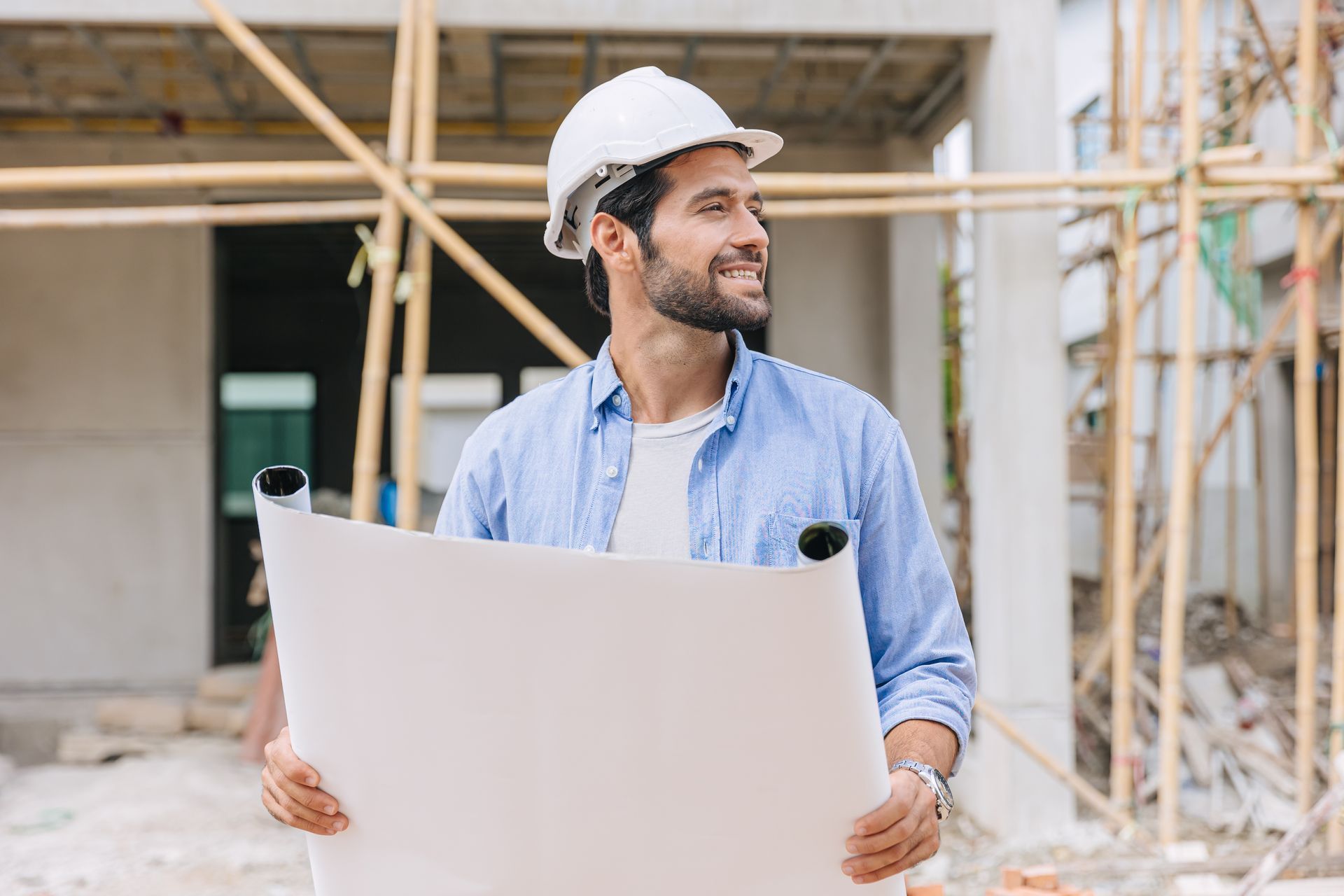 A man is holding a blueprint at a construction site.