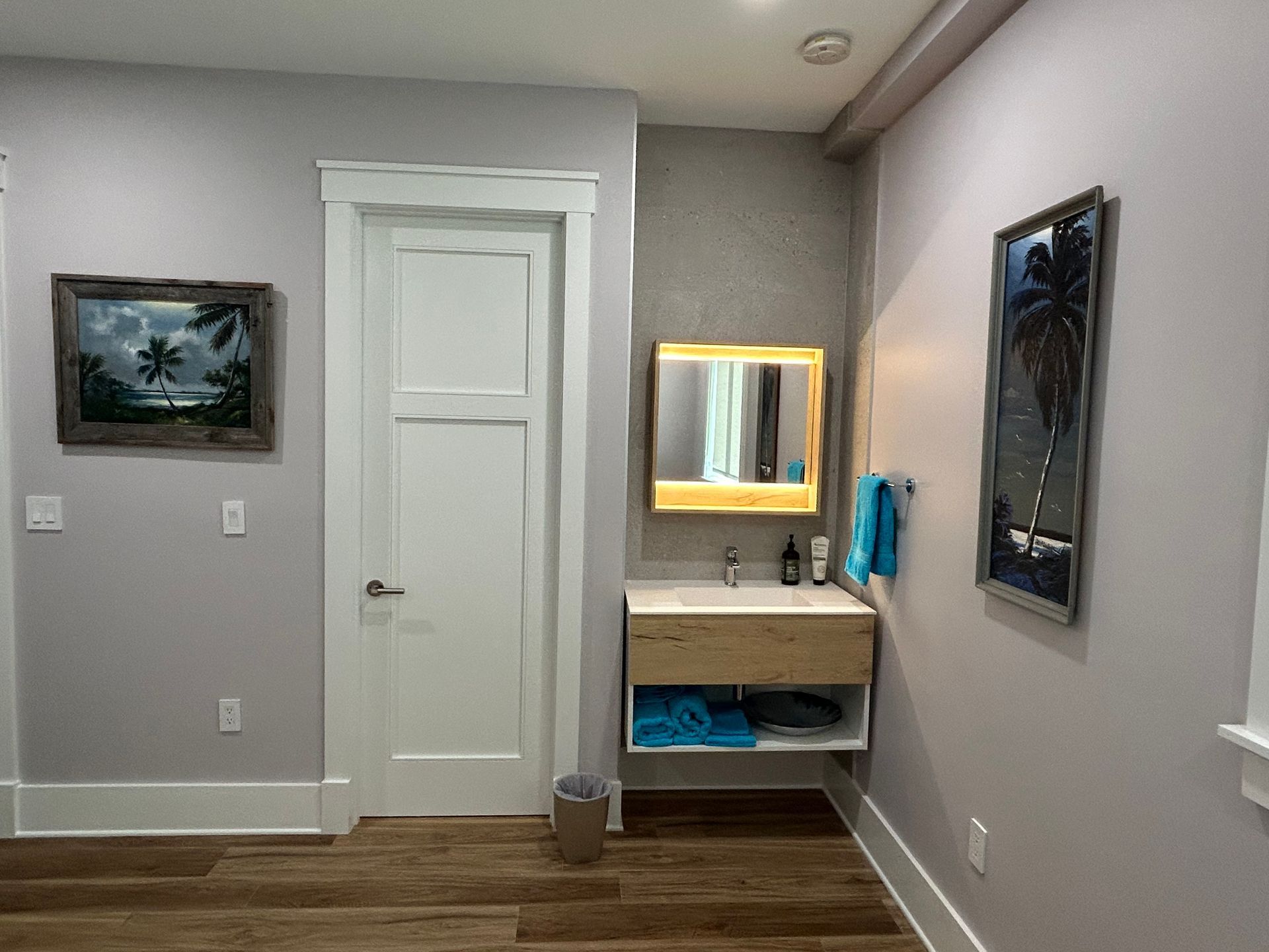 A bathroom with a sink , mirror and paintings on the wall.