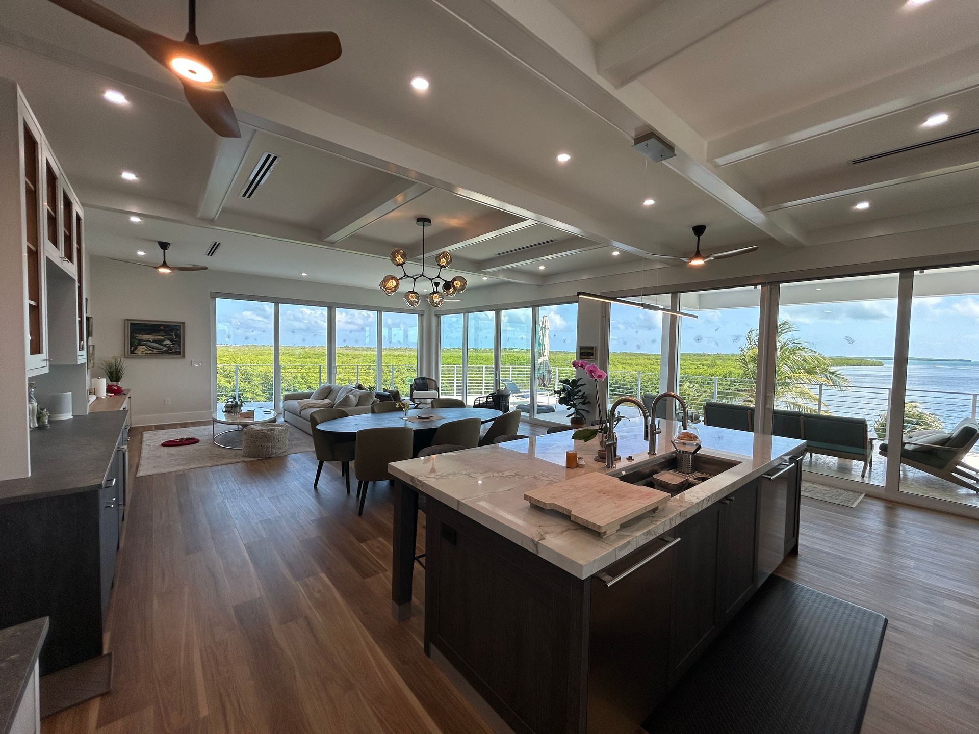 A large living room with a large island in the middle and a ceiling fan.