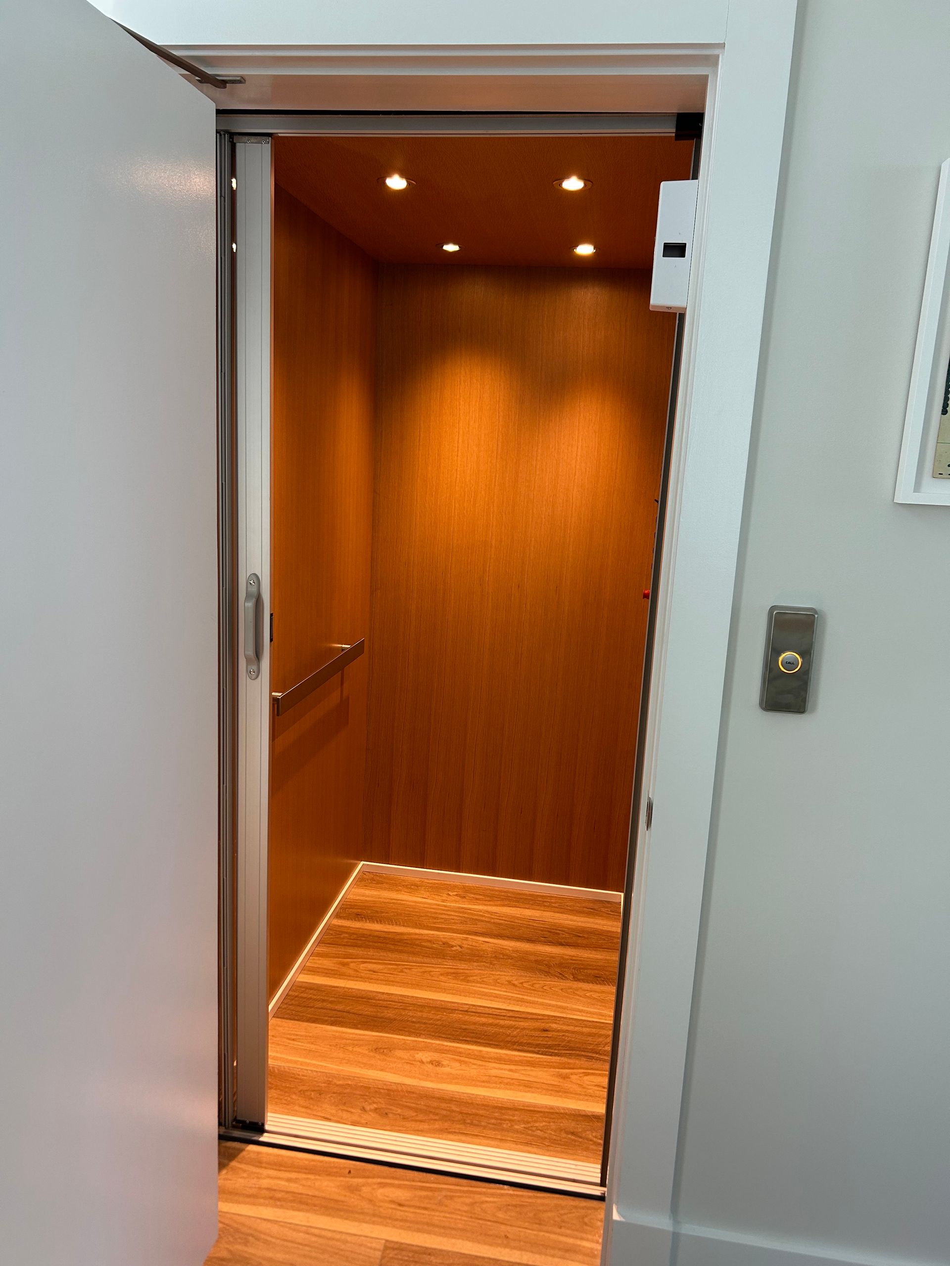 A wooden elevator with a wooden floor and a white door
