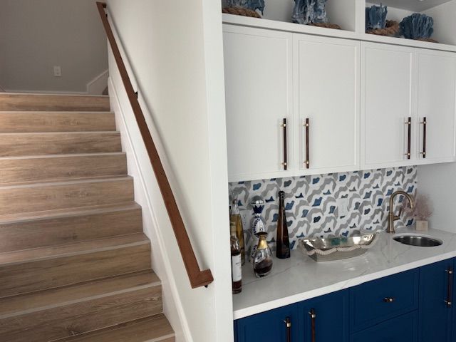 A kitchen with blue cabinets and white cabinets and stairs