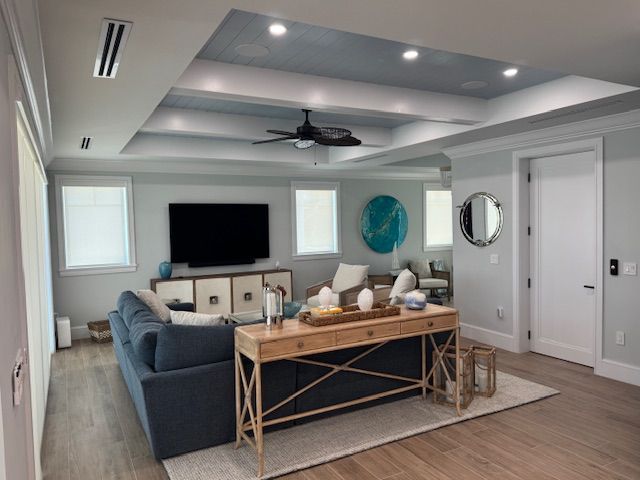 A living room with a couch , table , television and ceiling fan.