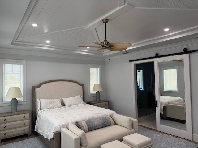 A bedroom with a ceiling fan and a sliding barn door