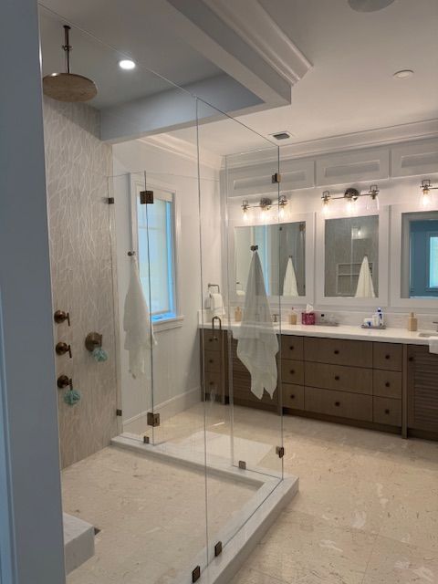 A bathroom with a walk in shower and two sinks