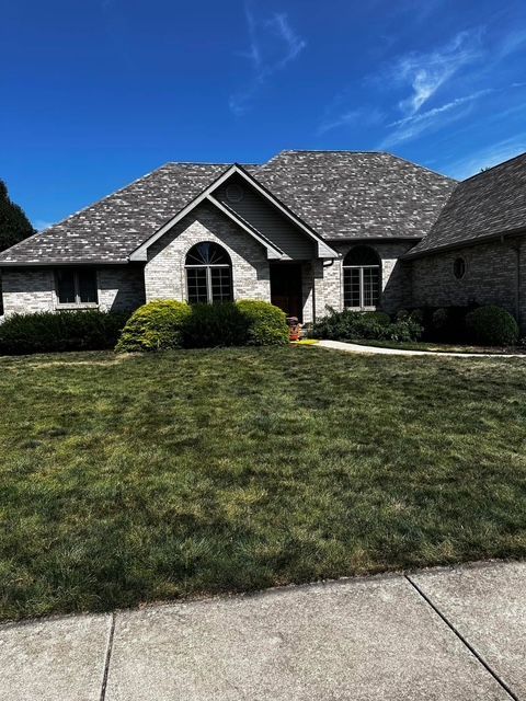 House with gray roof and brick exterior, arched windows, and green lawn under blue sky.