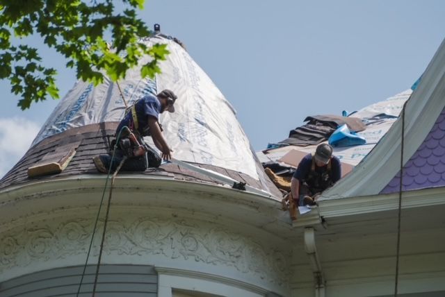 Two men are working on the roof of a house.