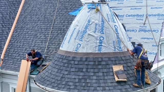 A group of men are working on a dome shaped roof.