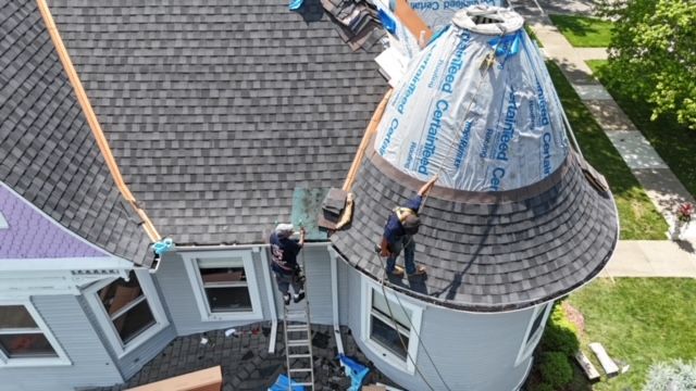A group of men are working on the roof of a house.