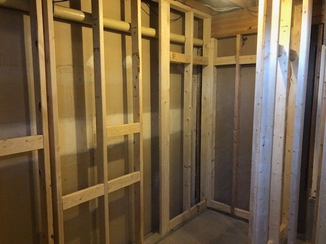 A view of interior wooden wall framing and wall studs in a room under construction.