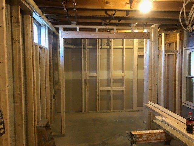 Interior view of a residential construction site featuring wooden wall framing and exposed ceiling joists.