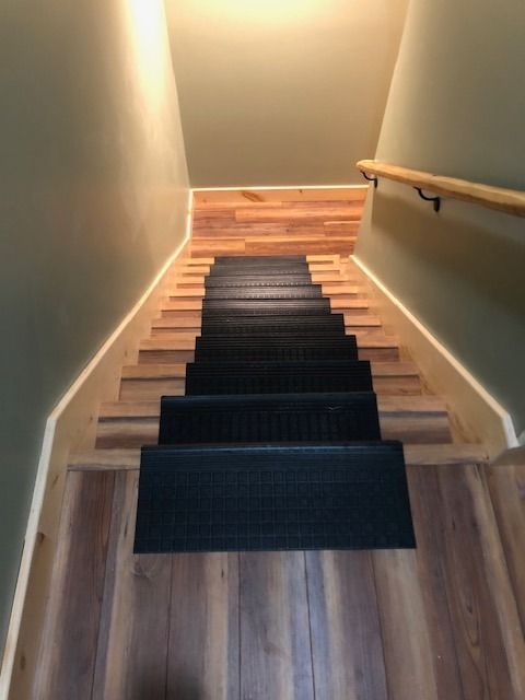 A staircase with wood steps, each featuring a black anti-slip rubber mat, leading down to a lower floor.