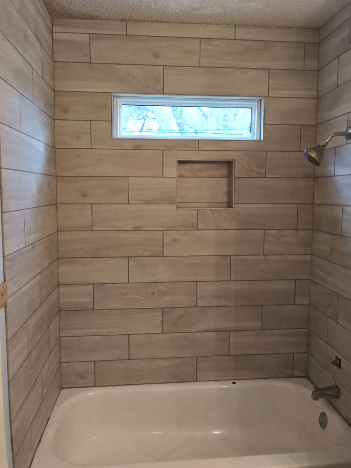 A bathroom with a tub and a shower with a window.