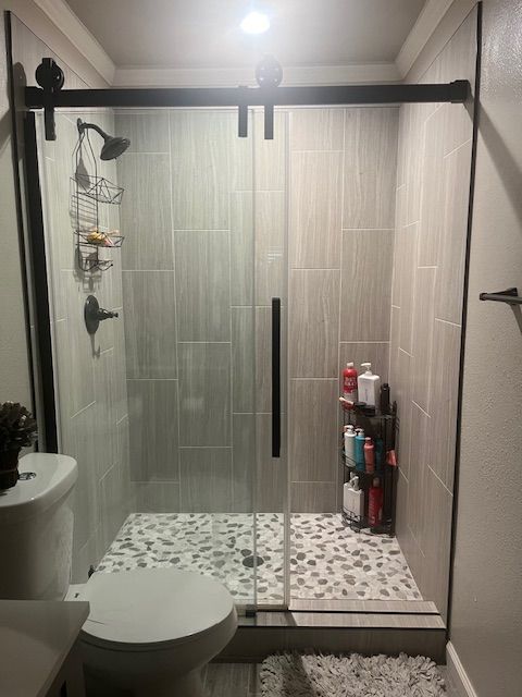 A bathroom with a toilet and a shower with a sliding glass door.