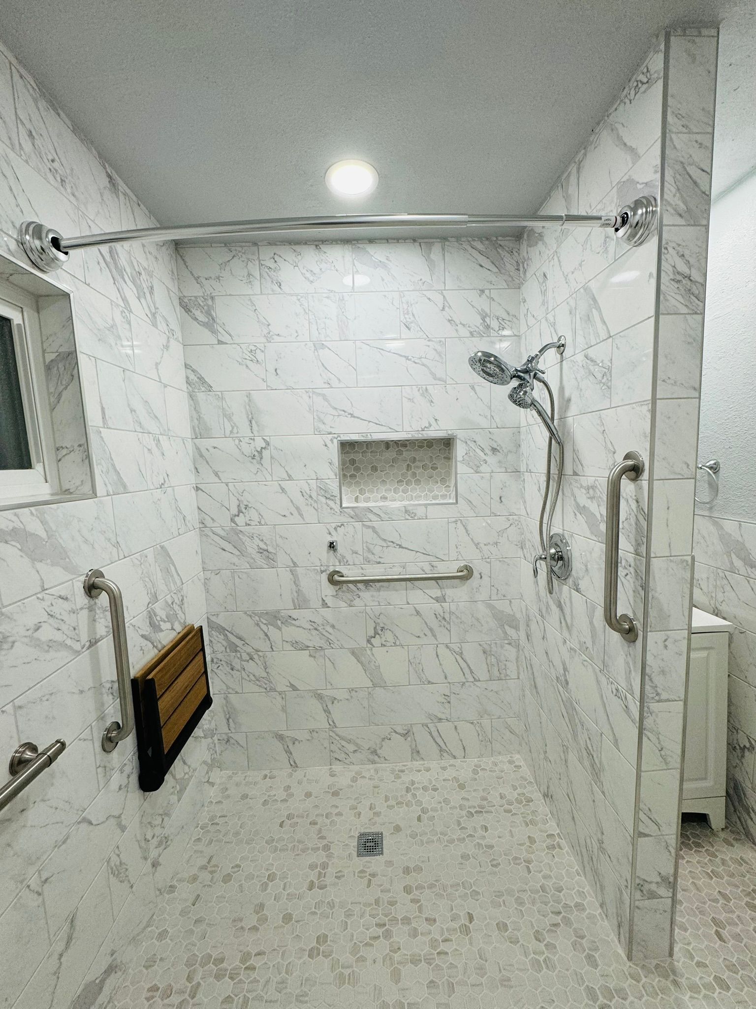 A bathroom with a walk in shower , a sink and a window.