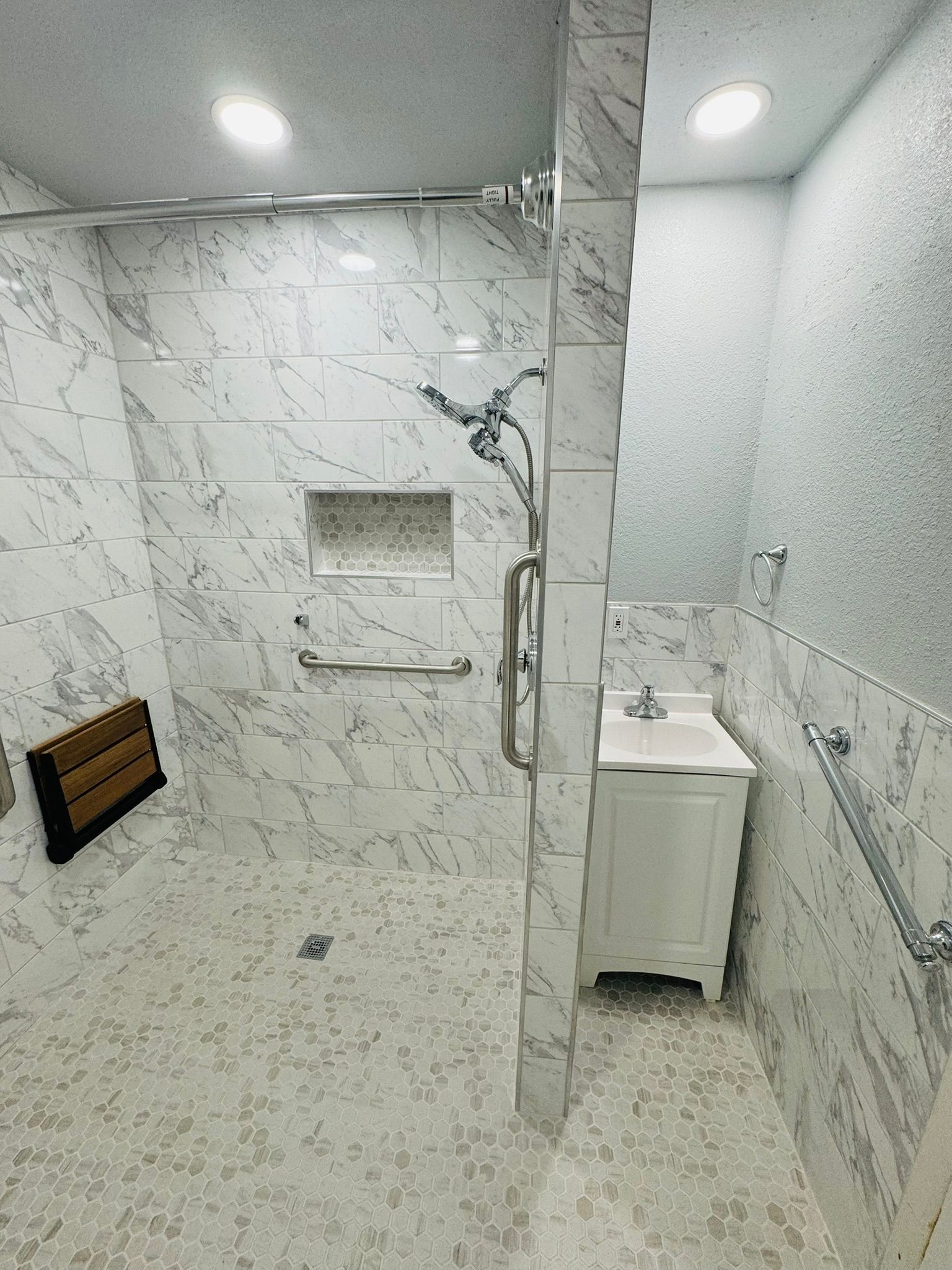 A bathroom with a walk in shower , sink and mirror.