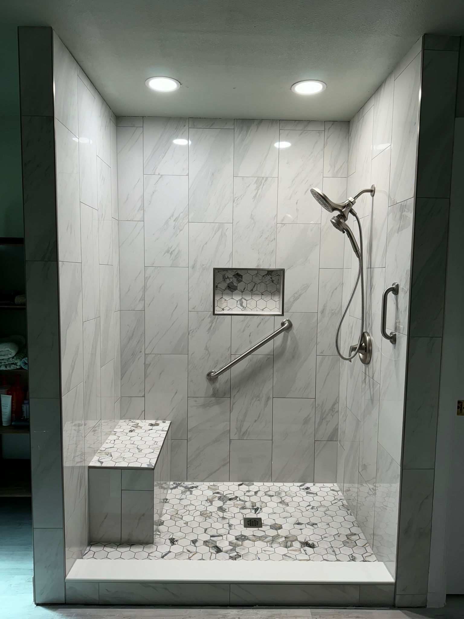 A walk in shower with a seat and a hand rail