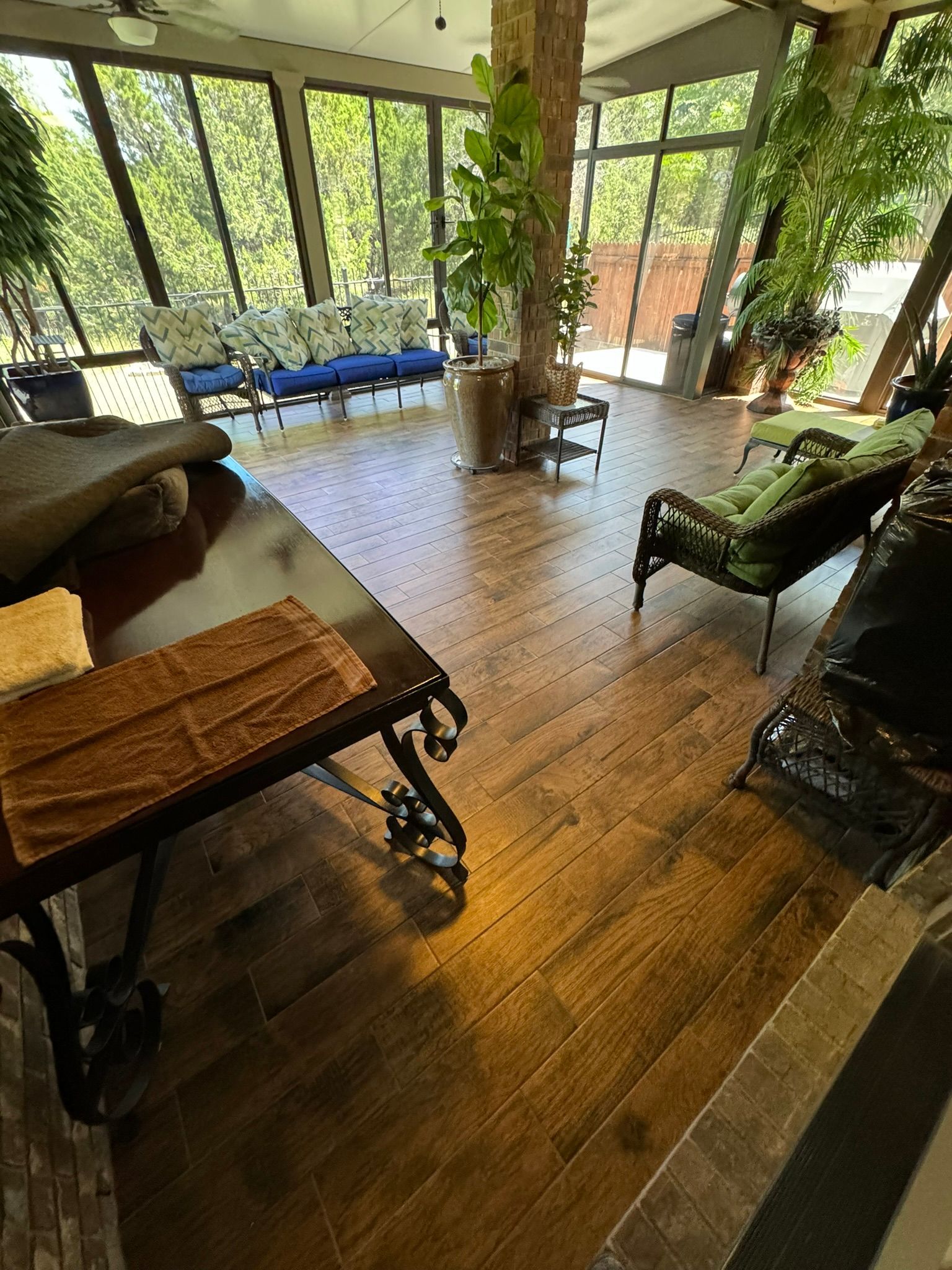 A living room with hardwood floors , a table , chairs , and a lot of windows.