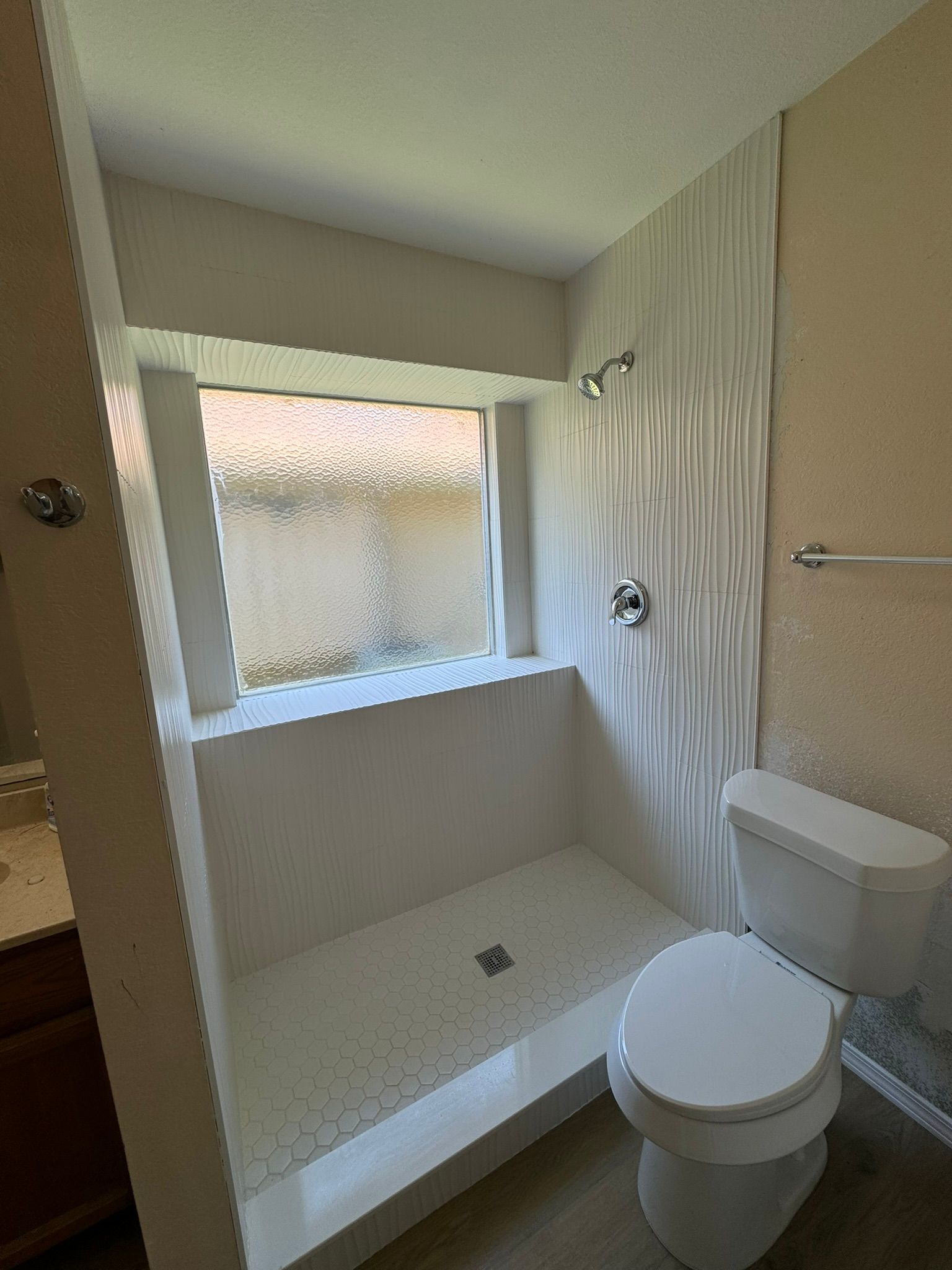 A bathroom with a toilet , shower and window.