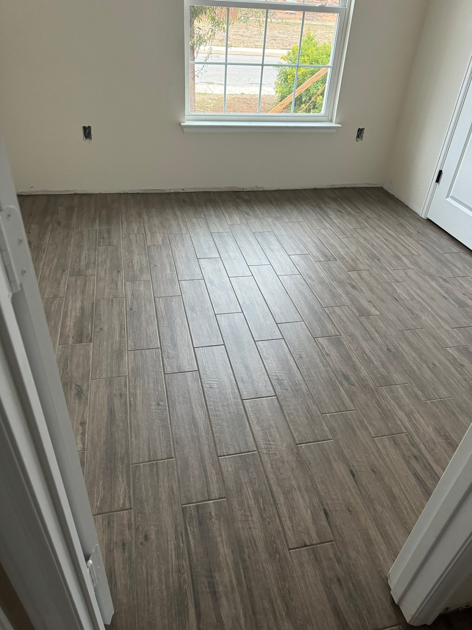 A room with a wooden floor and a window.