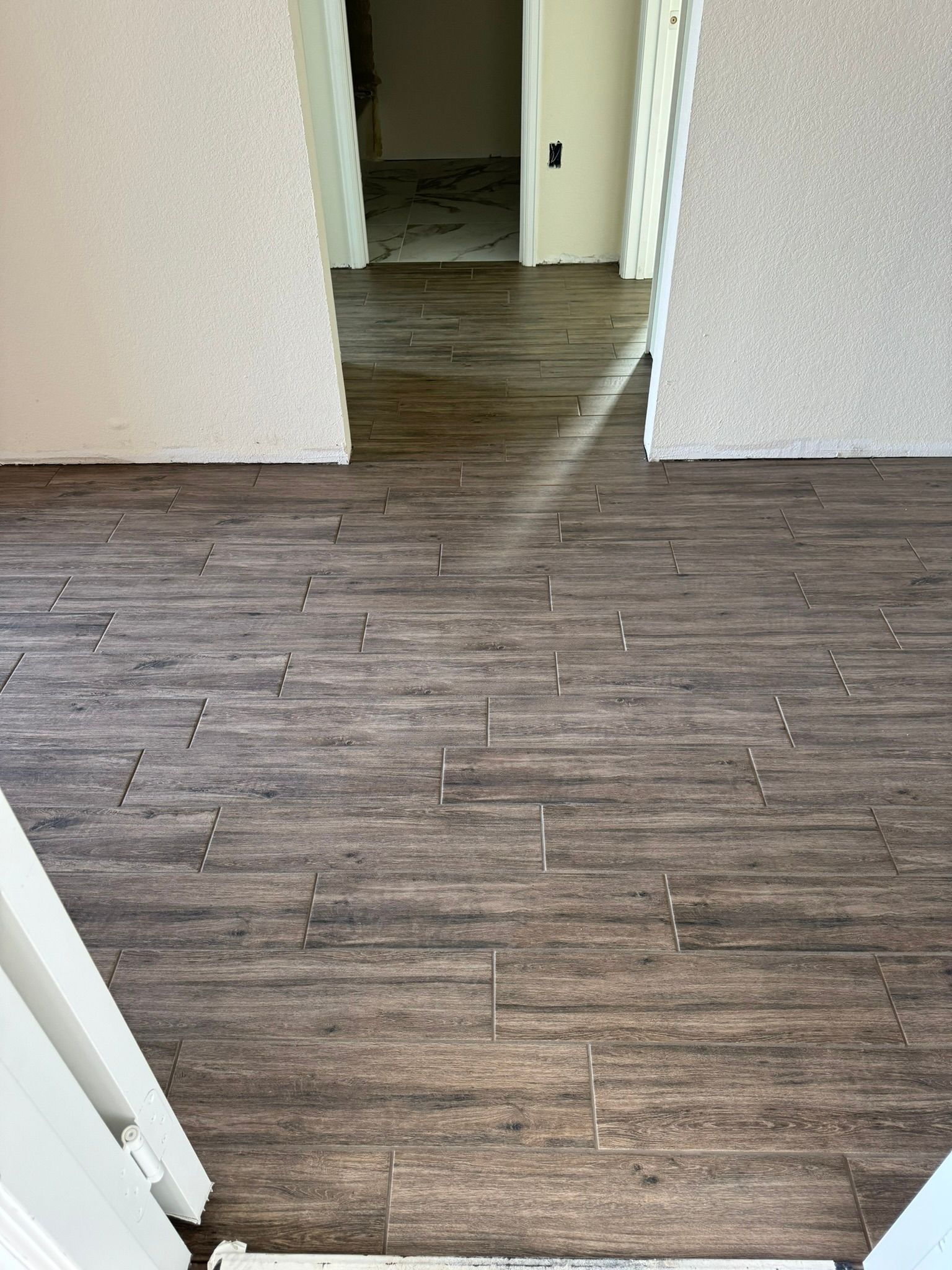 A room with a wooden floor and a doorway leading to a hallway.