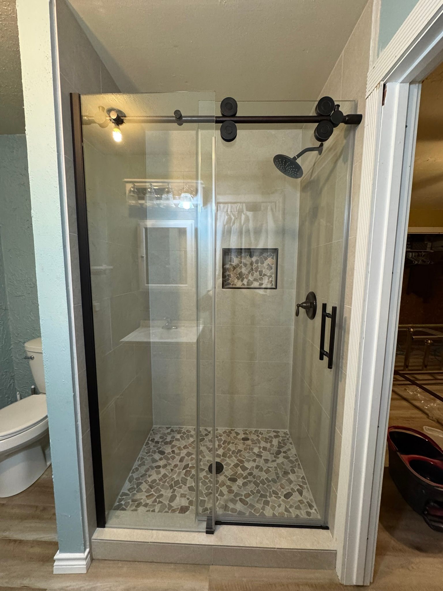 A bathroom with a sliding glass shower door and a toilet.
