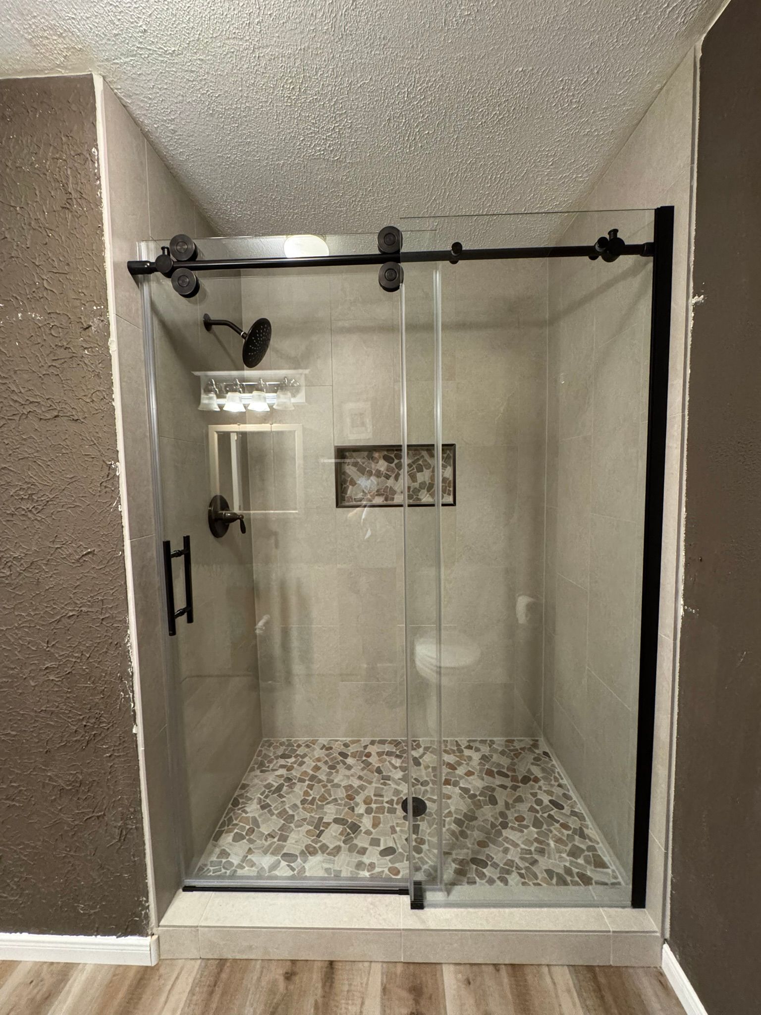 A bathroom with a sliding glass shower door.