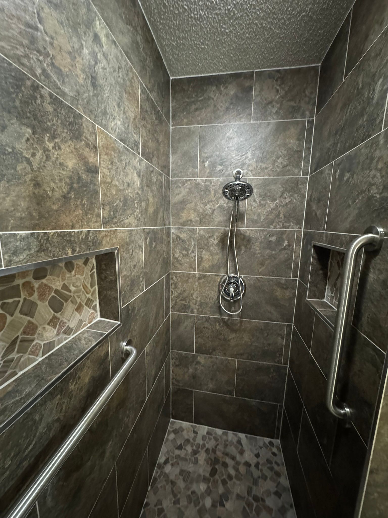 A bathroom with a walk in shower and a stainless steel handle.
