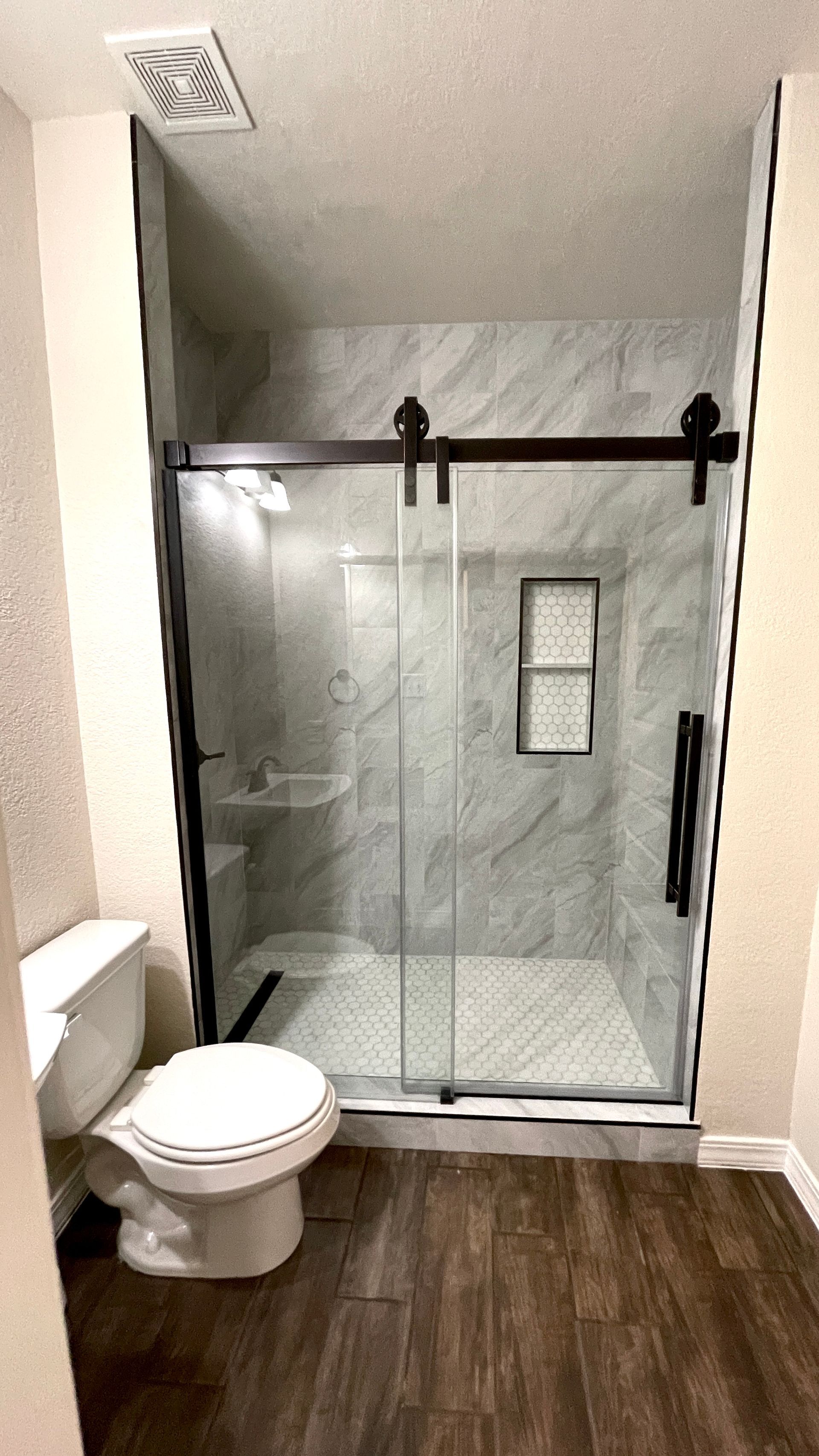 A bathroom with a toilet and a shower with a sliding glass door.