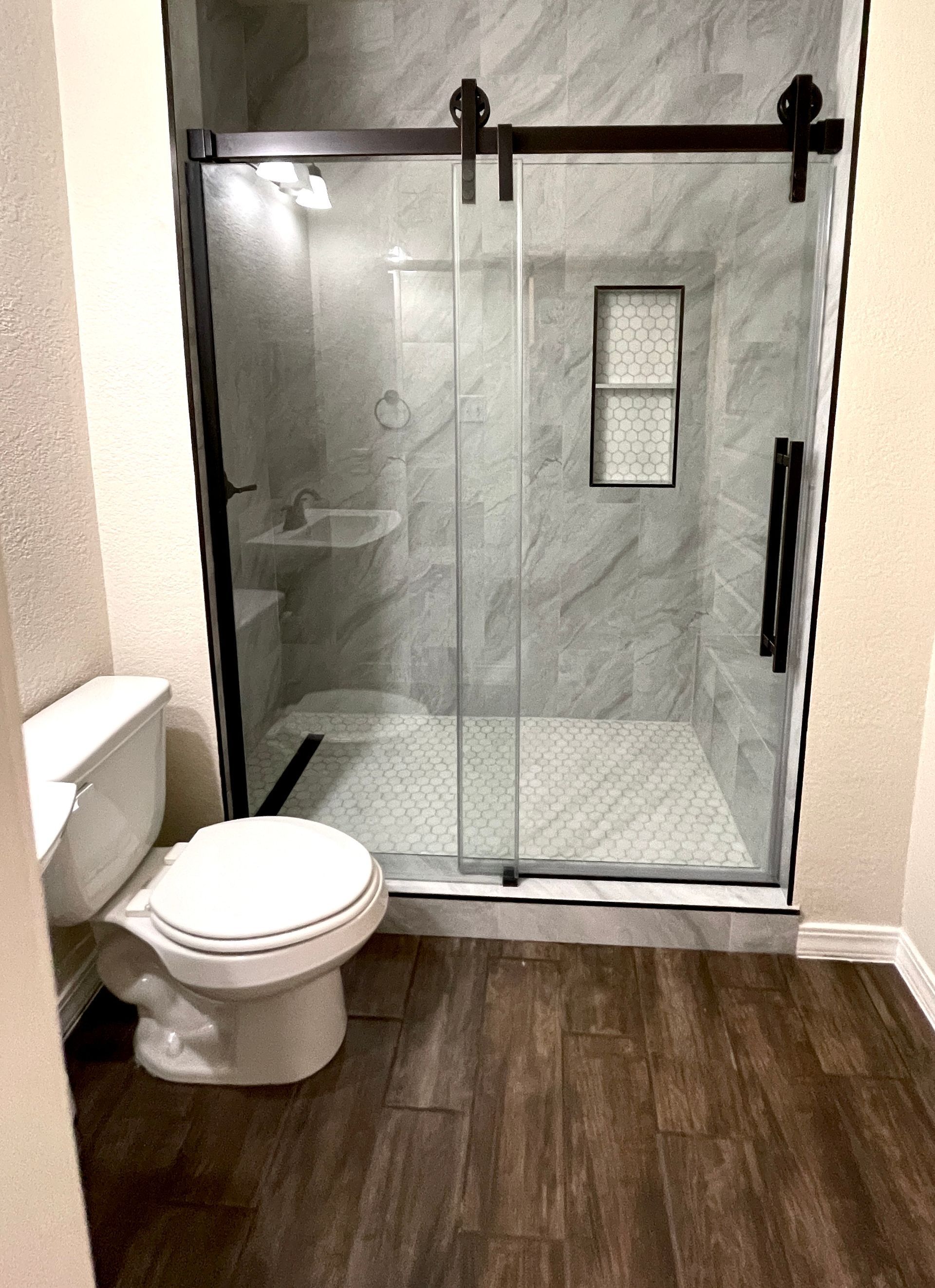 A bathroom with a toilet and a shower with a sliding glass door.