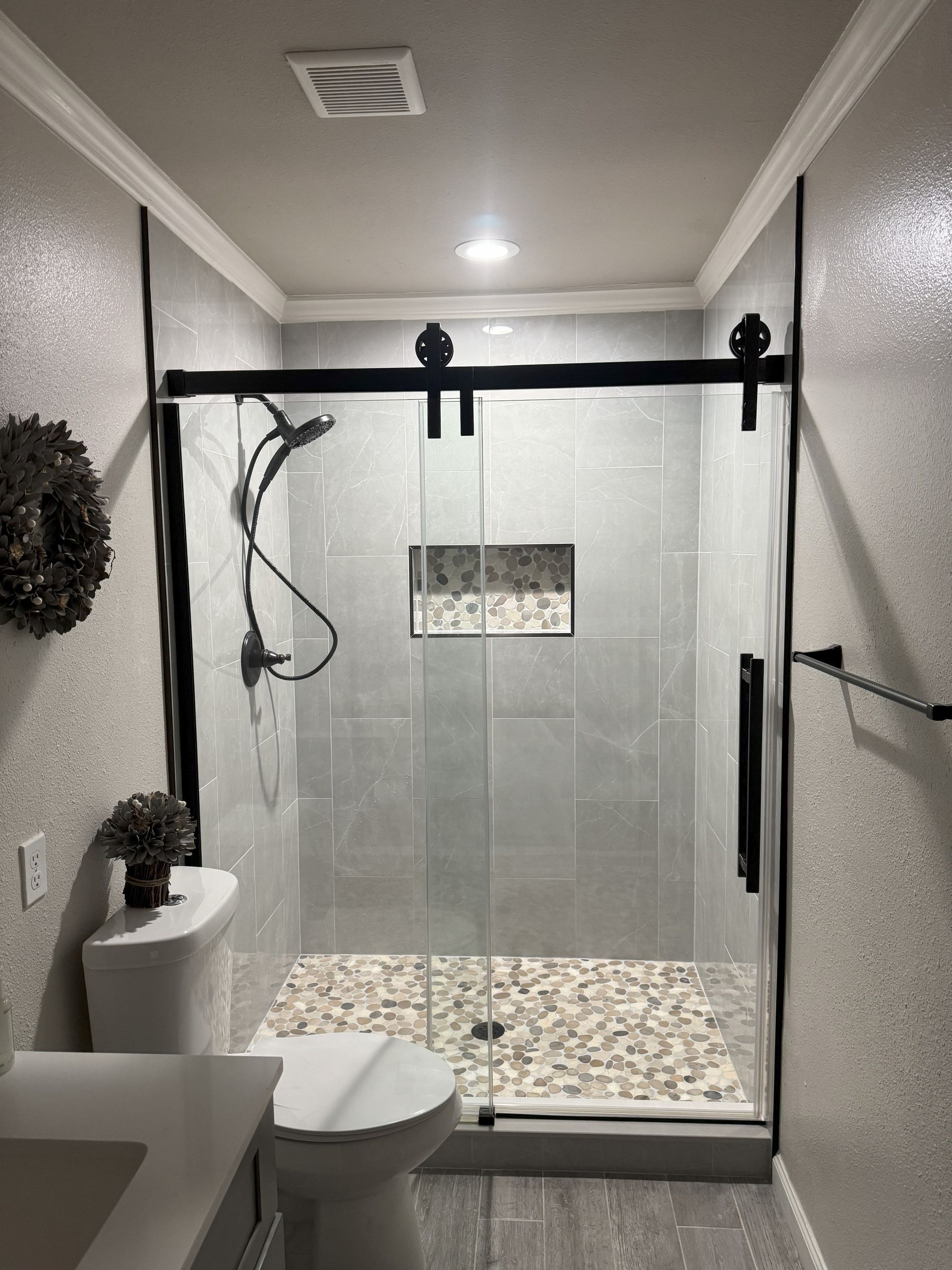 A bathroom with a sliding glass shower door and a toilet