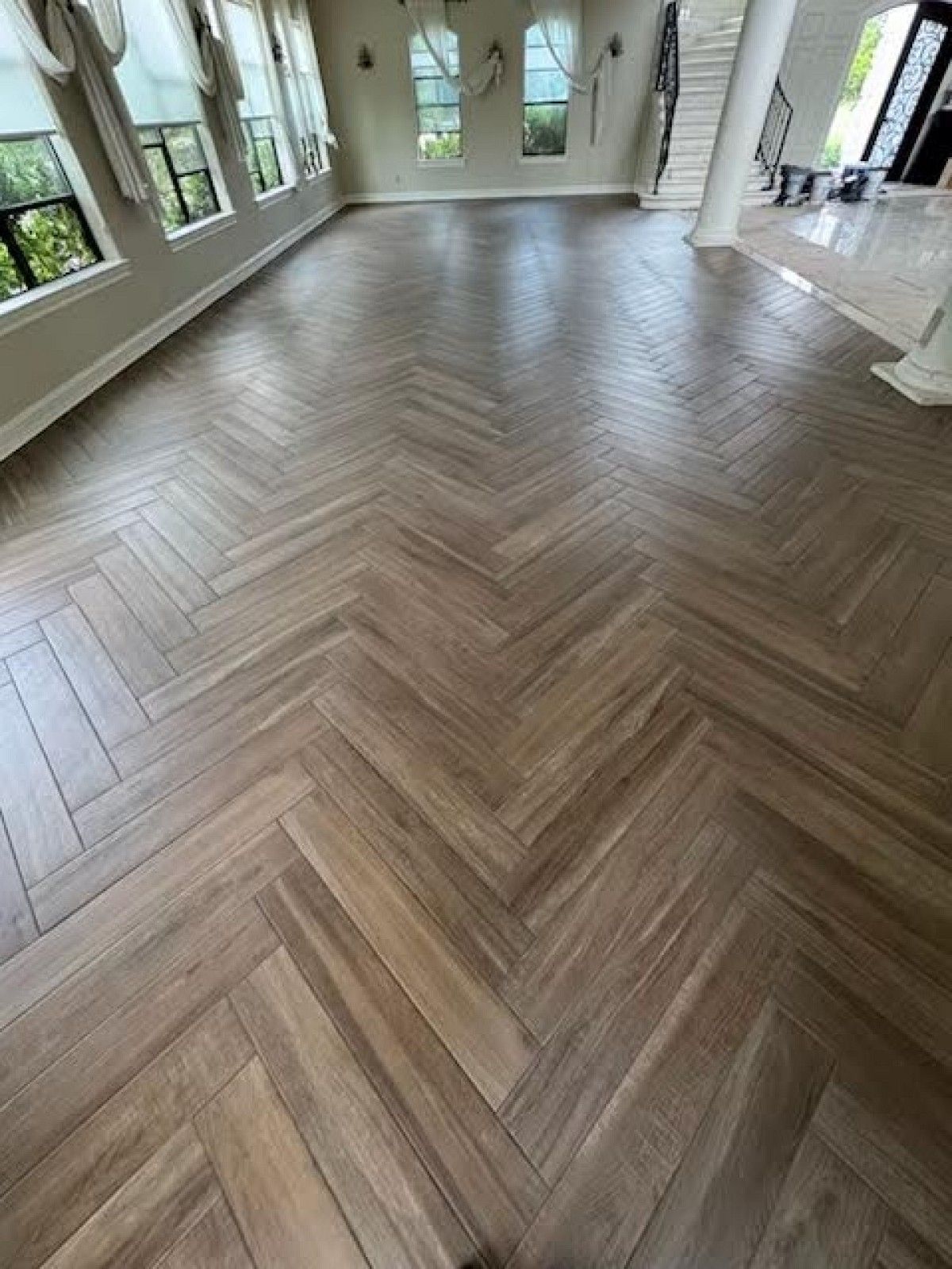 A living room with a wooden floor and a herringbone pattern.