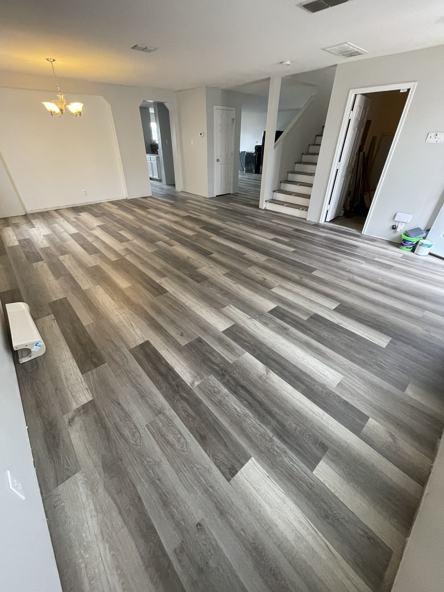 A living room with a wooden floor and stairs.