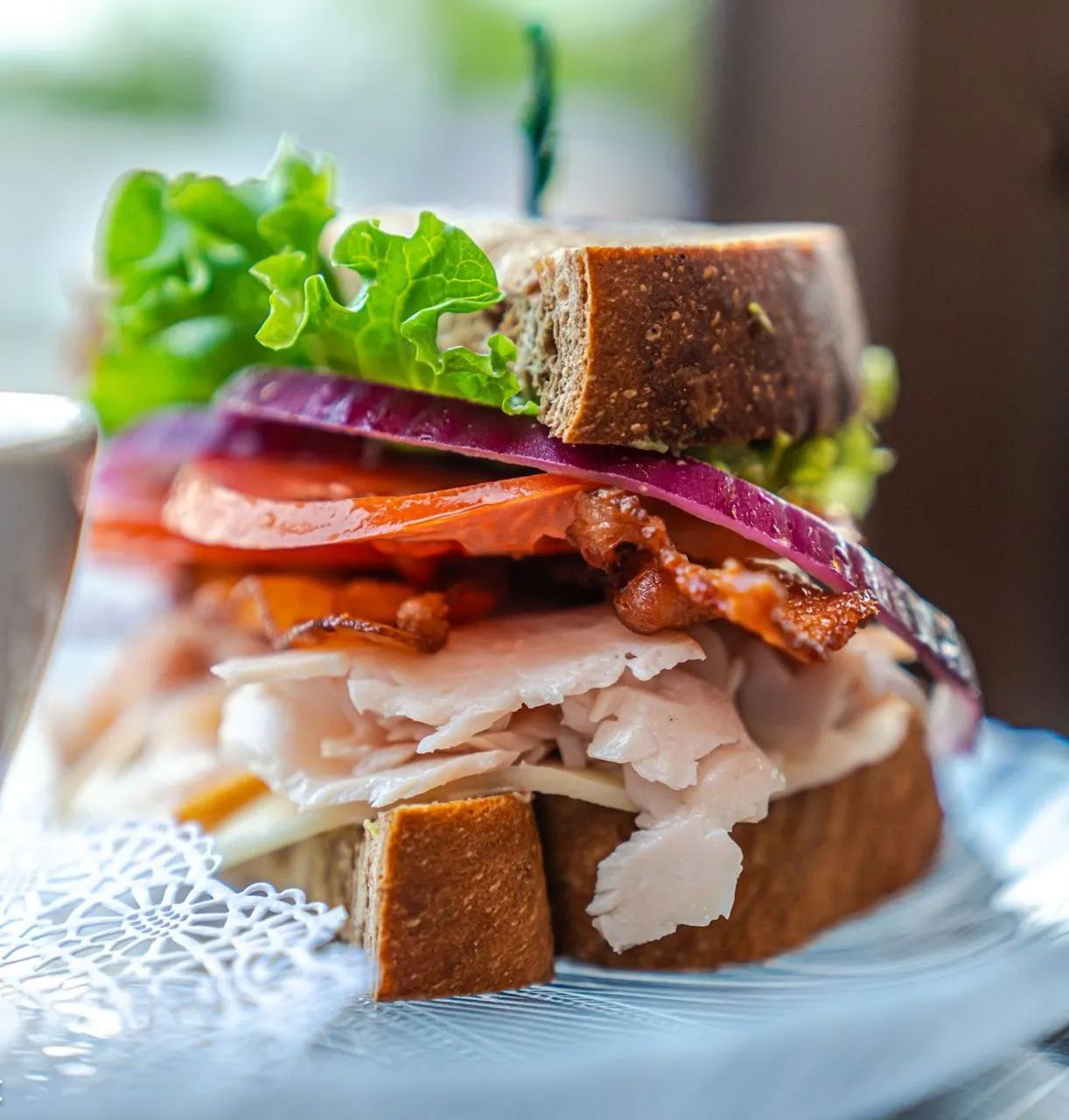 A sandwich with turkey , bacon , lettuce and tomatoes on a plate