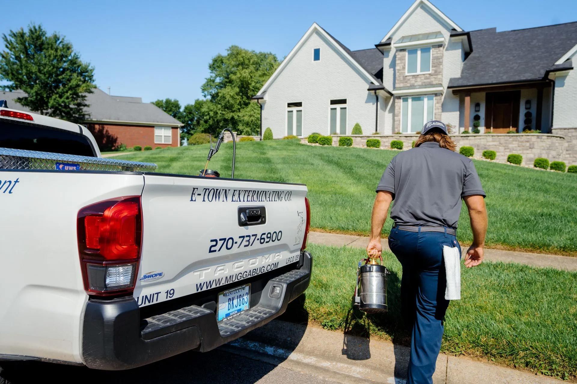 A man is walking towards a house with a truck in the background.
