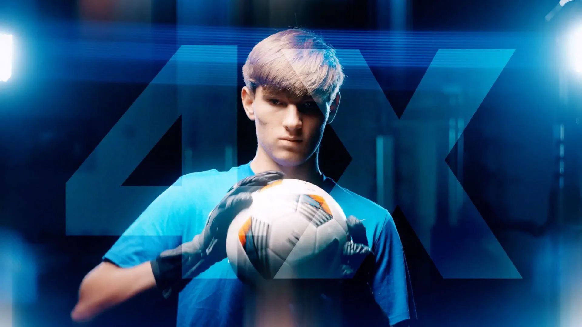 A young man in a blue shirt is holding a soccer ball.