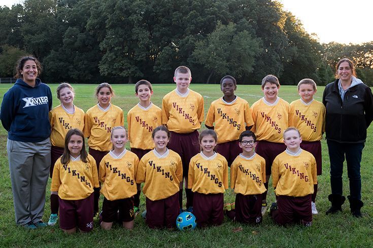A soccer team is posing for a picture on a field