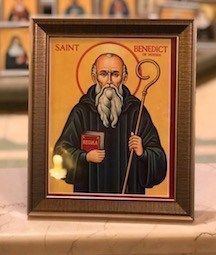 A framed icon of saint benedict is sitting on a table.