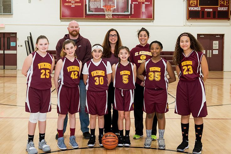 A group of young girls are posing for a picture on a basketball court.