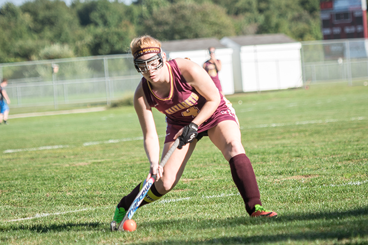 A woman is playing field hockey on a field.