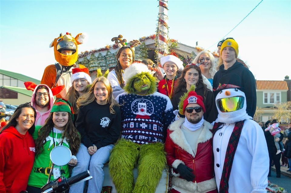 A group of people are posing for a picture with a grinch.