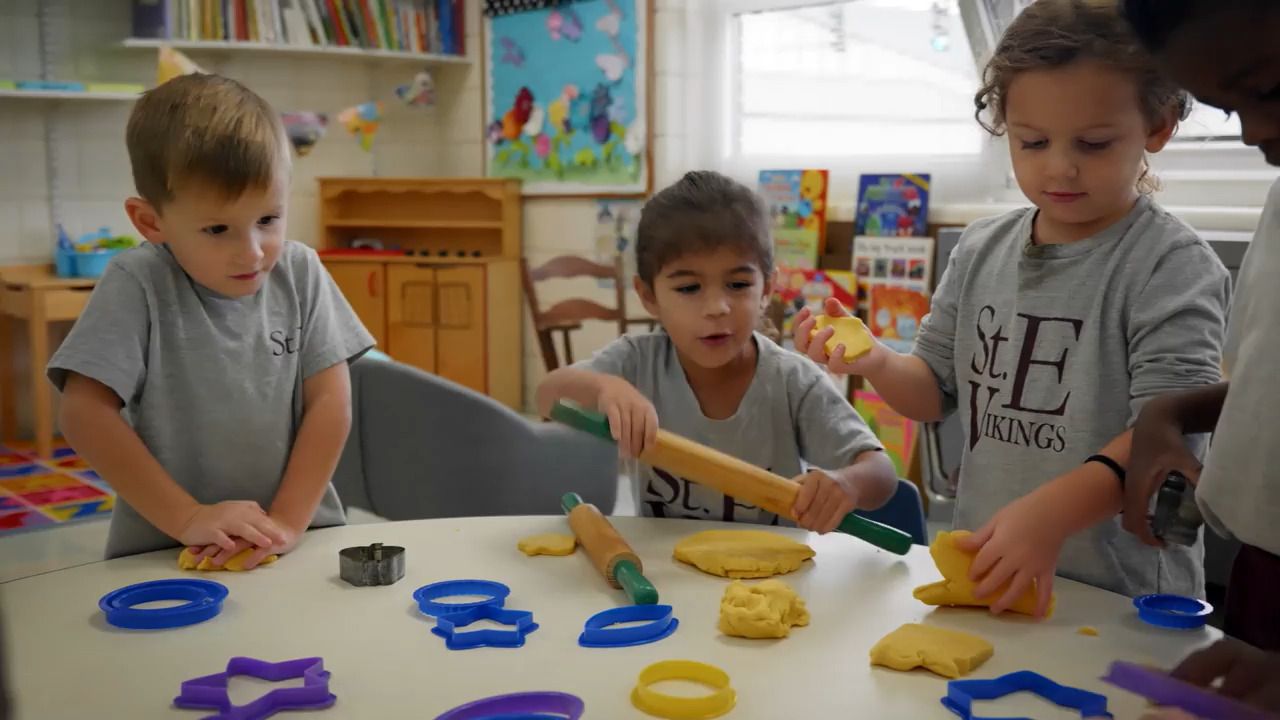 A group of children are playing with dough and cookie cutters at a table.